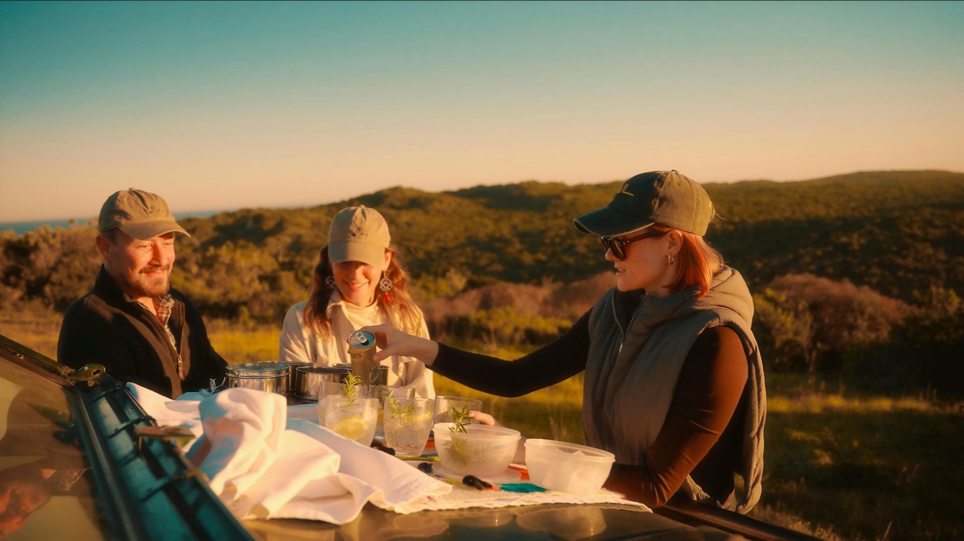 Sundowners served on the bonnet of a game-drive vehicle above the bush